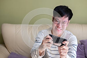 Selective focus at smartphone. Young adult Asian men laugh, smile and feeling happy while playing online game or watch movie on