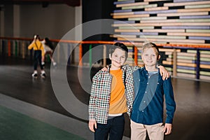 Selective focus of smiling boy hugging friend with skating girls