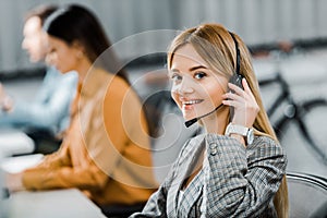 Selective focus of smiling call center operator looking at camera