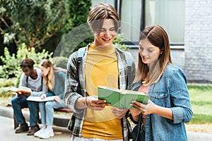 Focus of smiling teenagers reading book