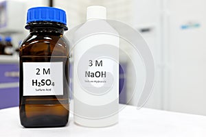 Selective focus of sodium hydroxide base and sulfuric acid solution in brown glass and plastic bottle photo