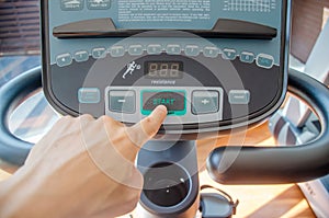 Selective focus `start`, Male hand pushes green start button on a threadmill control panel in the gym