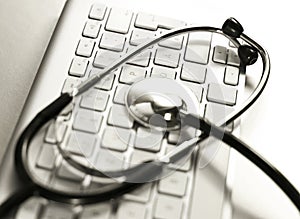 Selective focus of a stethoscope lying on a computer keyboard.