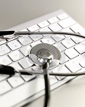 Selective focus of a stethoscope lying on a computer keyboard.