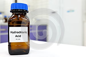 Selective focus of strong hydrochloric acid chemical in brown amber glass bottle inside a laboratory with copy space. photo