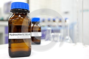 Selective focus of strong Hydrochloric acid solution in brown amber bottle. Blur laboratory backdrop with copy space.