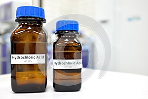 Selective focus of strong Hydrochloric acid solution in brown amber bottle. Blur laboratory backdrop with copy space.