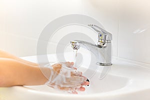 Selective focus of tap water children washing hands with soap un