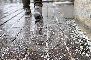 Closeup of technical salt grains on icy sidewalk surface in winter, used for melting ice and snow.