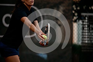 Selective focus on tennis ball and racket. Female tennis player prepares to serve during the match.