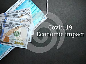 Selective focus.Text Covid-19 economic impact with face mask and banknote on a black background.Business concept idea.