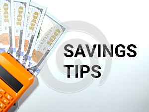 Selective focus.Text SAVINGS TIPS on a white background with calculator and fake dollar money.Savings concept idea.