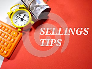 Selective focus.Text SELLINGS TIPS on a red background with calculator,clock and money.Business concept idea.