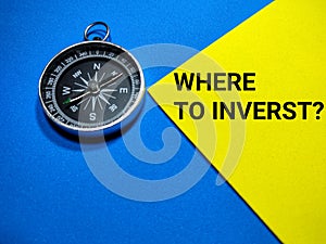 Selective focus.Text WHERE TO INVERST with compass on a blue and yellow background.