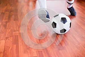 Selective focus to ball with futsal player run to shoot ball to goal on wooden floor in sport hall