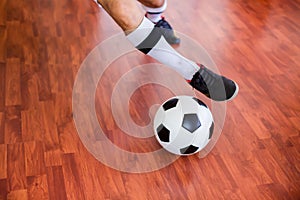 Selective focus to ball with futsal player run to shoot ball to goal on wooden floor in sport hall