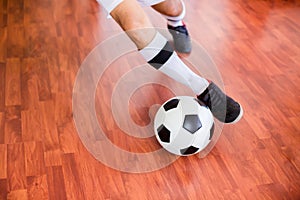 Selective focus to ball with futsal player run to shoot ball to goal on wooden floor in sport hall