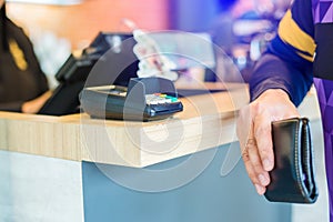 Selective focus to credit card reader with blurry wallet in hand of man. self service payment in modern shop, self-service pay