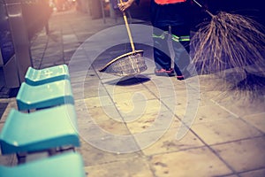 Selective focus to dustpan with blurry cleaning staff and broom