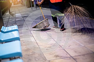 Selective focus to dustpan with blurry cleaning staff and broom