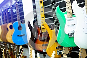 Selective focus to electric guitar with blurry guitars are hanging in musical showroom