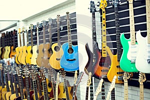 Selective focus to electric guitar with blurry guitars are hanging in musical showroom