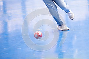 Selective focus to foot of futsal player with blurry red ball. Indoor soccer sports hall