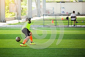 Selective focus to goalkeeper is jumping to catching the soccer ball. Blurry ball after going out from hands of goalkeeper on