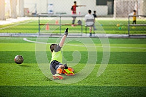 Selective focus to goalkeeper is jumping to catching the soccer ball. Blurry ball after going out from hands of goalkeeper on