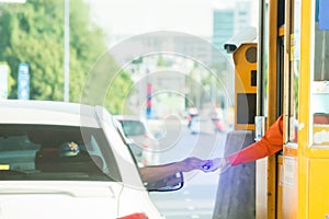 Selective focus to hand of driver pay for the expressway. Driver pays money to a cashier for a toll road or toll gate motorway