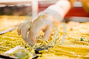 Selective focus to hand is selecting gold jewelry, customers are buying gold jewelry
