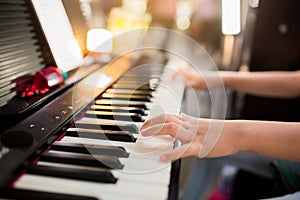 Selective focus to kid`s hand playing piano on stage