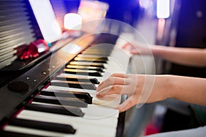 Selective focus to kid`s hand playing piano on stage