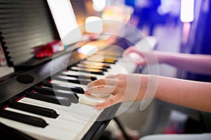 Selective focus to kid`s hand playing piano on stage