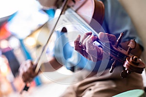 Selective focus to an old musician's hand is playing the violin. Street musician