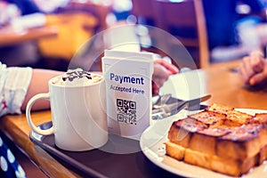 Selective focus to QR code payment tag with blur bread set meal and coffee in coffee shop or restaurant to accepted generate