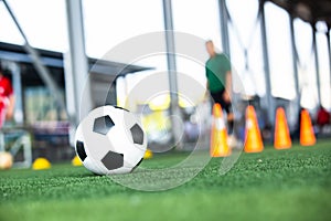 Selective focus to soccer ball on green artificial turf with blurry soccer team is training