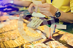 Selective focus to staff are counting banknote, customers are buying gold jewelry in the gold shop