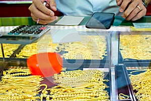 Selective focus to staff hand will writing sale order of gold jewelry in the gold shop