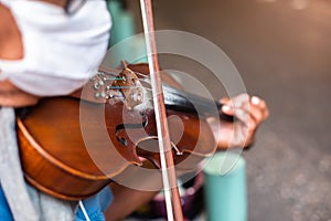 Selective focus to the violin with an old musician is playing it. Street musician