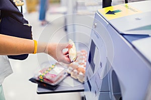 Selective focus to the woman is scanning the product at the automatic payment machine