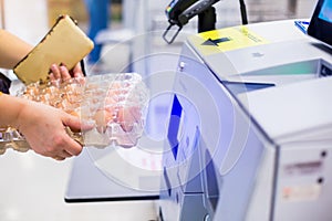 Selective focus to the woman is scanning the product eggs at the automatic payment machine