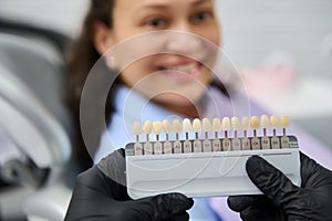 Selective focus on tooth color chart in the hands of a dentist, choosing the shade of veneers, according to Vita scale.