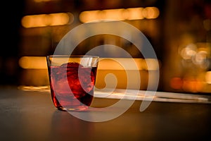 selective focus of transparent glass of cocktail with piece of ice stands on a bar counter