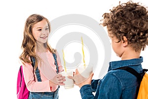 Selective focus of two schoolkids holding milkshakes isolated on white.