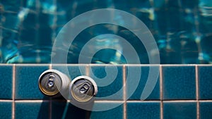 Selective focus Two white beer cans are placed at the edge of the pool with space for text input. The water surface in the blue