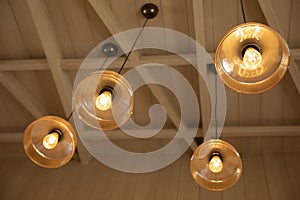 Selective focus and up view shot with copy space of vintage ceiling lamp hung on wooden ceiling with light bulb shows shining