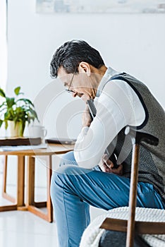 Selective focus of upset senior man hugging photo album near