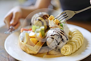 selective focus, Use fork to eat waffles served with mixed fruits, sliced banana, ice-cream