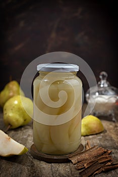 Selective focus vertical shot of pickled pears inside a glass jar with pears around